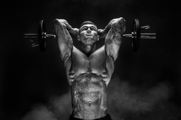 Portrait of muscular man lifting dumbbell. Studio shot. Exercise for triceps. Motivation.