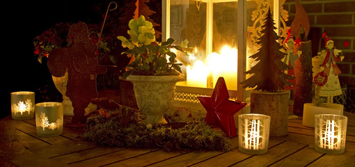 Weihnachtliche Dekoration mit Christrose und Windlicht und Kerzenschein