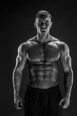 Fototapeta na wymiar Very brawny guy bodybuilder posing. Beautiful sporty guy male power. Fitness muscled man in studio. Dark background.