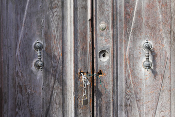 Fototapeta premium Two closed padlocks with a chain on an old wooden door
