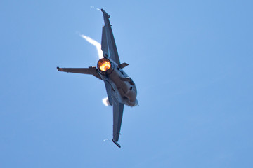 Extremely close view of a F-16 Fighting Falcon in a high G turn, with condensation streaks at the wing roots, with afterburner on 