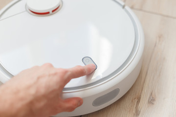 Man press button to command robot vacuum cleaner