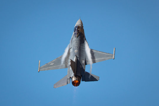 Extremely close view of a F-16 Fighting Falcon in a high G turn, with condensation streaks at the wing roots, with afterburner on 