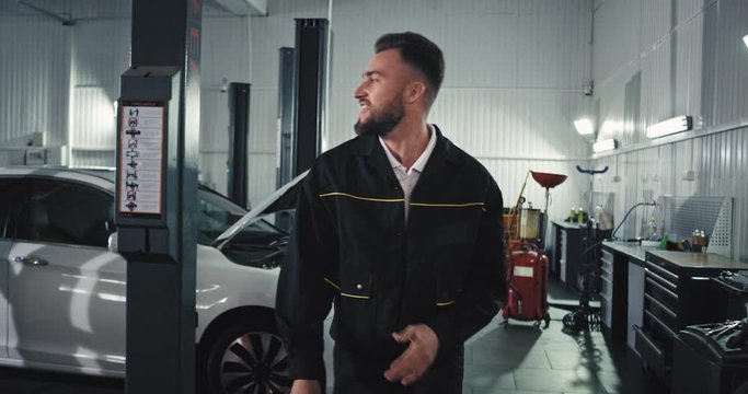 Service auto worker mechanic enjoying the day at work while fixing the car he dancing and moving funny in front of the camera
