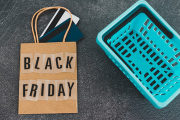 black friday shopping bag with payment cards and shopping basket next to it