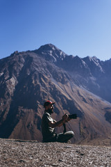 Fototapeta premium stylish bearded man with camera in hands on top of Georgian mountains: nature photographer traveler taking photo of beautiful landscape from top of the mountain