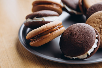Close up Traditional chocolate and Pumpkin Whoopie pies filled made with vanilla cream cheese in cozy cafe background