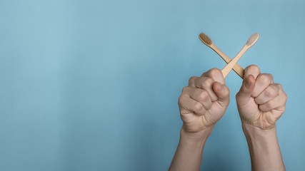 Hands crossed wooden toothbrushes on Gently blue background. Stop pollution. New generation. Bamboo Eco Friendly Biodegradable Toothbrush. The concept of Zero Waste, healthy teeth, eco-friendly