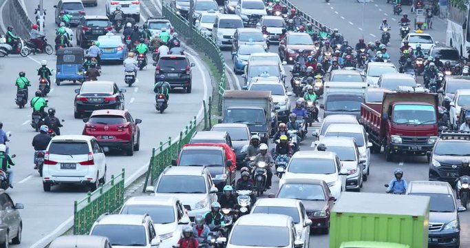 JAKARTA, Indonesia - November 27, 2019: Aerial view of traffic jam in rush hour on highway with numerous cars and motorcycle driver. Shot in 4k resolution from a drone