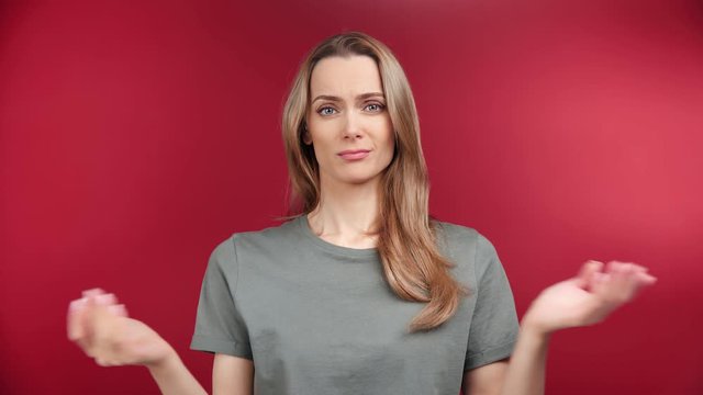 Portrait of perplexity young woman feeling misunderstanding emotion posing at red studio background
