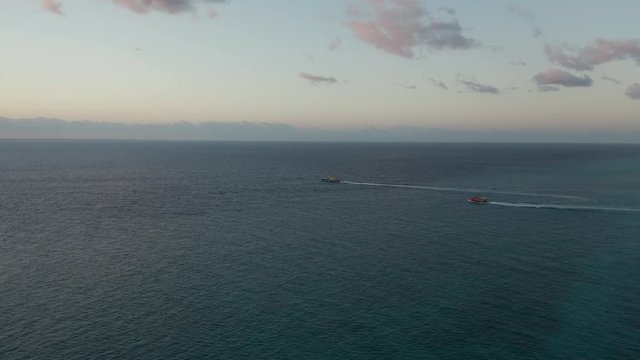 Aerial Footage Following Two Boats Out to Sea at Sunrise - Side View
