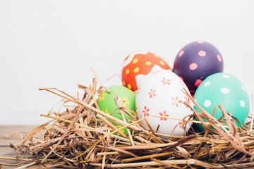 Naklejka na ściany i meble Beautiful Easter multi color egg in straw on wooden