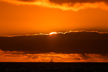 Natural marine landscape with amazing sunset over the ocean in Tenerife Canary Island Spain. Summer exotic vacation postcard from tropical island. Wonderful orange sunrise over the water behind clouds