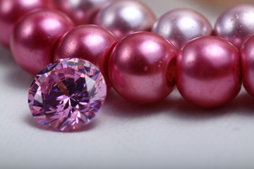 Close up shoot of an engagement ring on a pink pearl bracelet