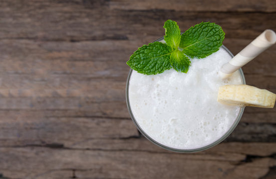 Coconut blend banana milk smoothie drink fresh cocktail shake milkshake vanilla juice fruit beverage food healthy the taste yummy In glass on wooden background from top view.