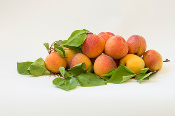 Fresh apricots with leaves on white background