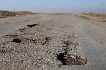 road in desert. Potholes in the pavement on a rural road. Poor  road concept