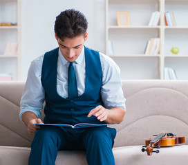 Young musician man practicing playing violin at home