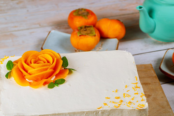 Festive cake with white whipped cream and slices of ripe persimmon.