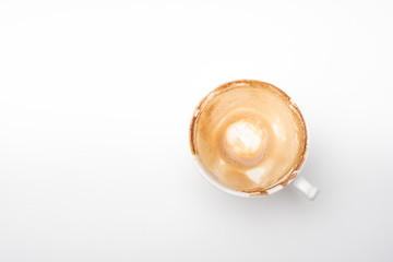 A cup of hot latte coffee that is completely drained on a white background.