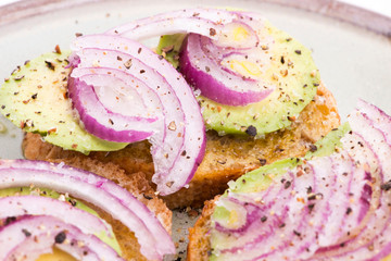 Sandwich with fresh avocado and onion on a plate