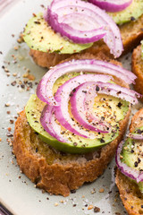 Sandwich with fresh avocado and onion on a plate