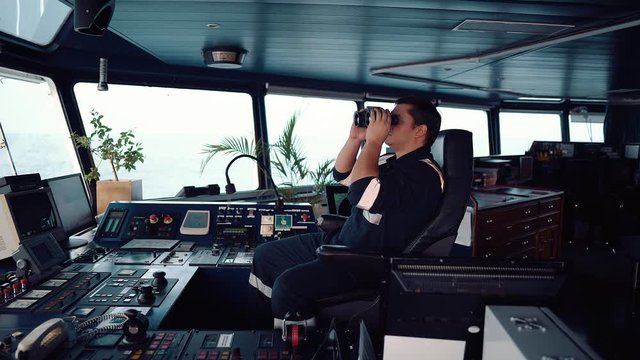 Navigational officer lookout on navigation watch looking through binoculars. Marine industry. COLREG collision regulations