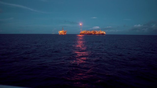 FPSO tanker vessel near Oil Rig platform. Offshore oil and gas industry. Flare is burning with smoke. View from supply vessel.