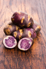 White - violet potato on wooden background. Organic plant