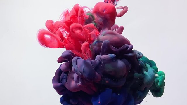 Amazing slow-motion video red, blue and green watercolor inks spin beautifully in water. Powerful explosion of paints on a white background. The smooth movement of acrylic ink in water. 
