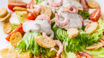 Food banner. Close-up appetizing salad with shrimp, lettuce, cheese, avocado and crackers on a white plate. Delicious and healthy seafood recipes. Low calories