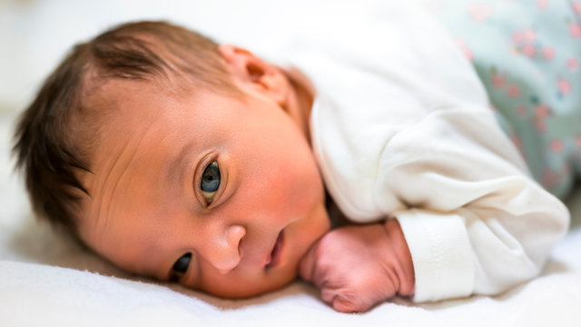A close portrait of a beautiful baby lying on his tummy.