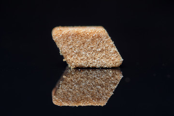 A piece of refined sugar with cinnamon on a black background. Photographed close-up.