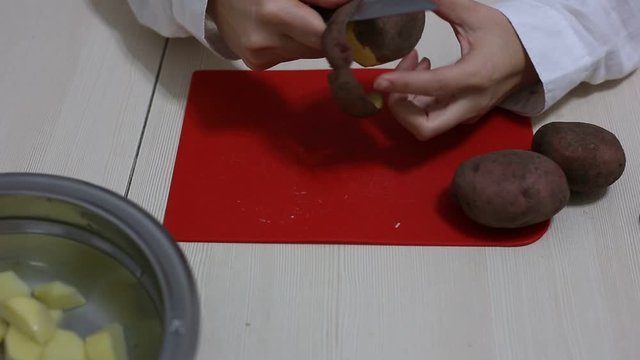 Woman hands peeling of poteto.