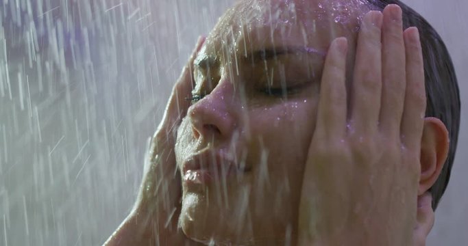 Close up of an young sensual blond hair woman is taking a hot relaxing shower in a luxury wellness center.