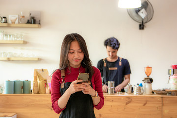 Portrait of a smiling young Asian female entrepreneur standing with her smartphone or cellphone