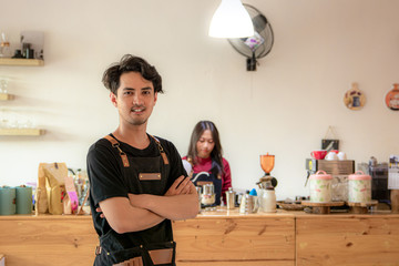 Portrait of a smiling young Asian male entrepreneur standing with her arms crossed