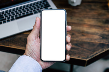 Mockup image blank white screen cell phone.men hand holding texting using mobile on desk at home office. background empty space for advertise text.people contact marketing business and technology 