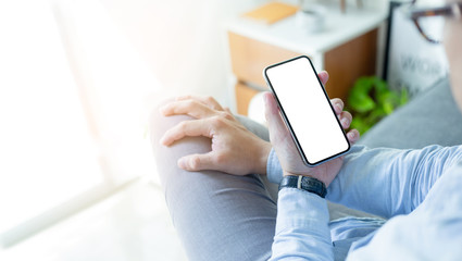 Mockup image blank white screen cell phone.men hand holding texting using mobile on desk at home office. background empty space for advertise text.people contact marketing business and technology 