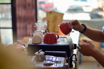 portrait of handsome asian barista inside cafe counter doing his job making a coffee latte