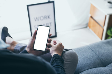 Mockup image blank white screen cell phone.men hand holding texting using mobile on desk at home office. background empty space for advertise text.people contact marketing business and technology 