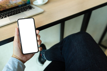 Mockup image blank white screen cell phone.men hand holding texting using mobile on desk at home office. background empty space for advertise text.people contact marketing business and technology 