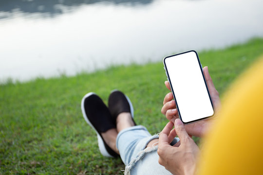 Mockup image blank white screen cell phone.men hand holding texting using mobile sitting in park.background empty space for advertise text.people contact marketing business and technology 