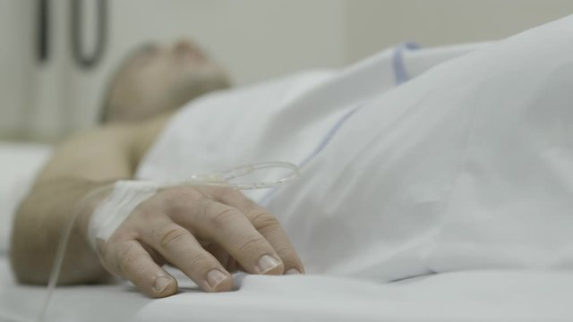 Unconscious young Caucasian male, lying 
on bed and responding with finger