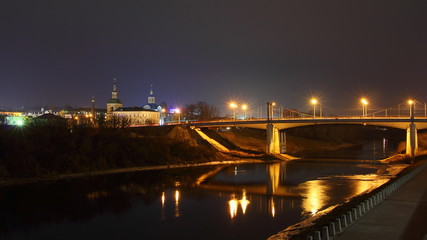 Fototapeta premium Russia, Smolensk famous landmark Uspensky Bridge across Dnieper river with reflection street lights, embankment Park and Church, beautiful wide autumn night view from City Observation deck