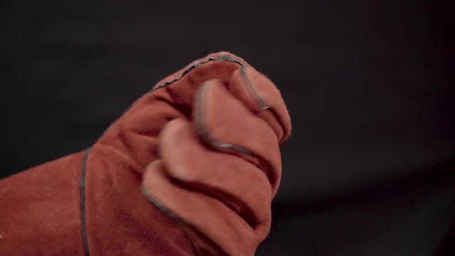 Big working new gloves made of rough suede. Special Welder Gloves. Wear work gloves. Hand of a man close-up on a dark background.