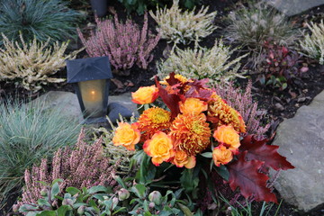 Mit Blumen geschmücktes Grab im Herbst