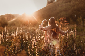 caucasian girl with long hair in field at sunset