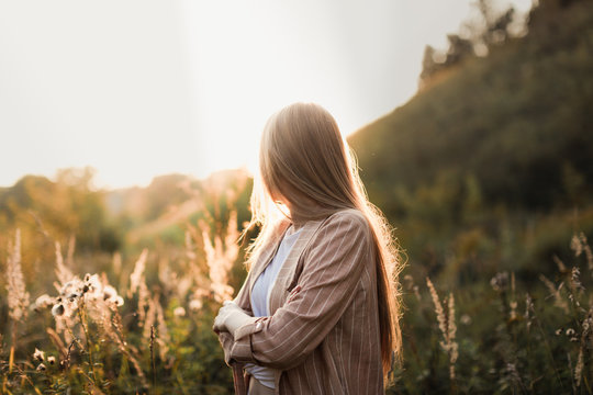 caucasian girl with long hair in field at sunset