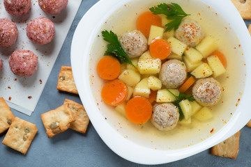 Close-up of soup with meatballs, potato, carrots and parsley, view from above, horizontal shot